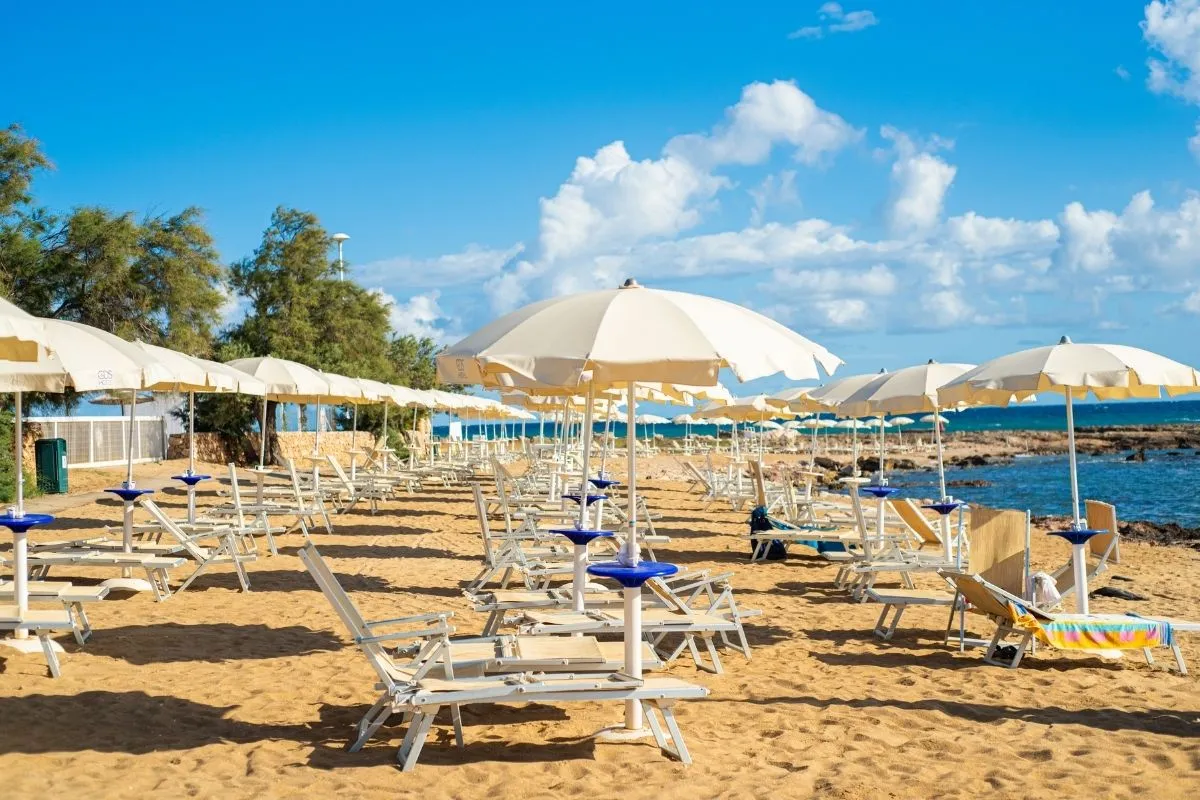 File di lettini e ombrelloni sulla spiaggia di sabbia dorata vista mare