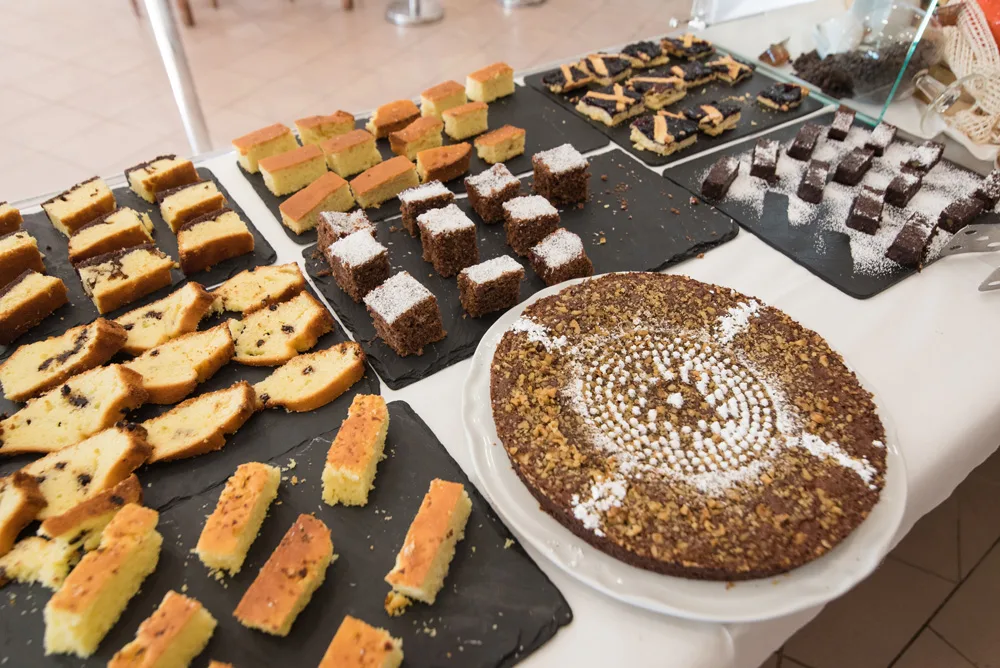 Buffet di dolci con torte, plumcake e tortine assortite su vassoi di ardesia
