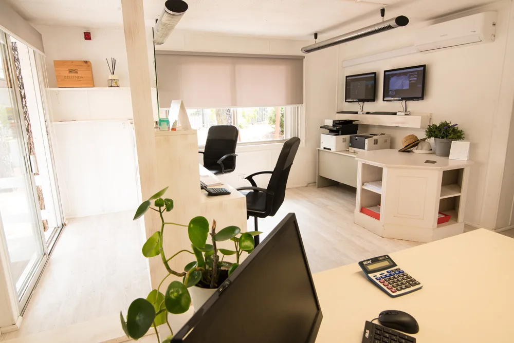 Ufficio reception con scrivanie, monitor di sorveglianza e piante decorative