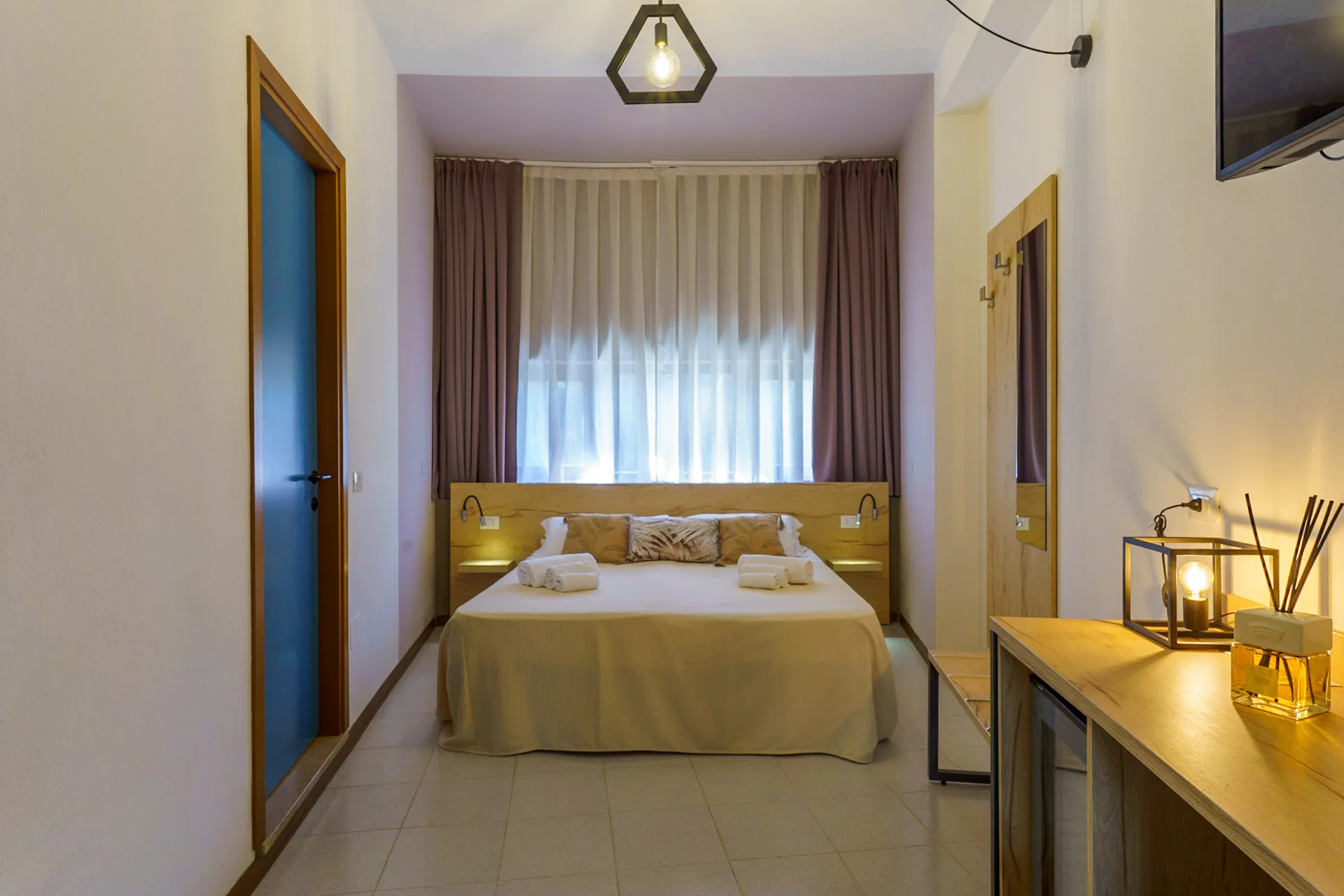 Camera matrimoniale accogliente con letto centrale, tende e illuminazione soffusa
