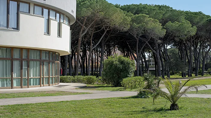 Esterno dell'edificio circolare del complesso con prato verde e pineta