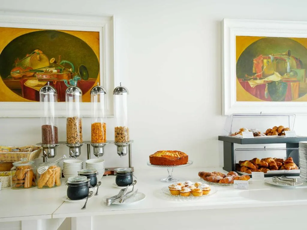 Buffet dolce della colazione con torte, cornetti, cereali e biscotti su tavolo bianco