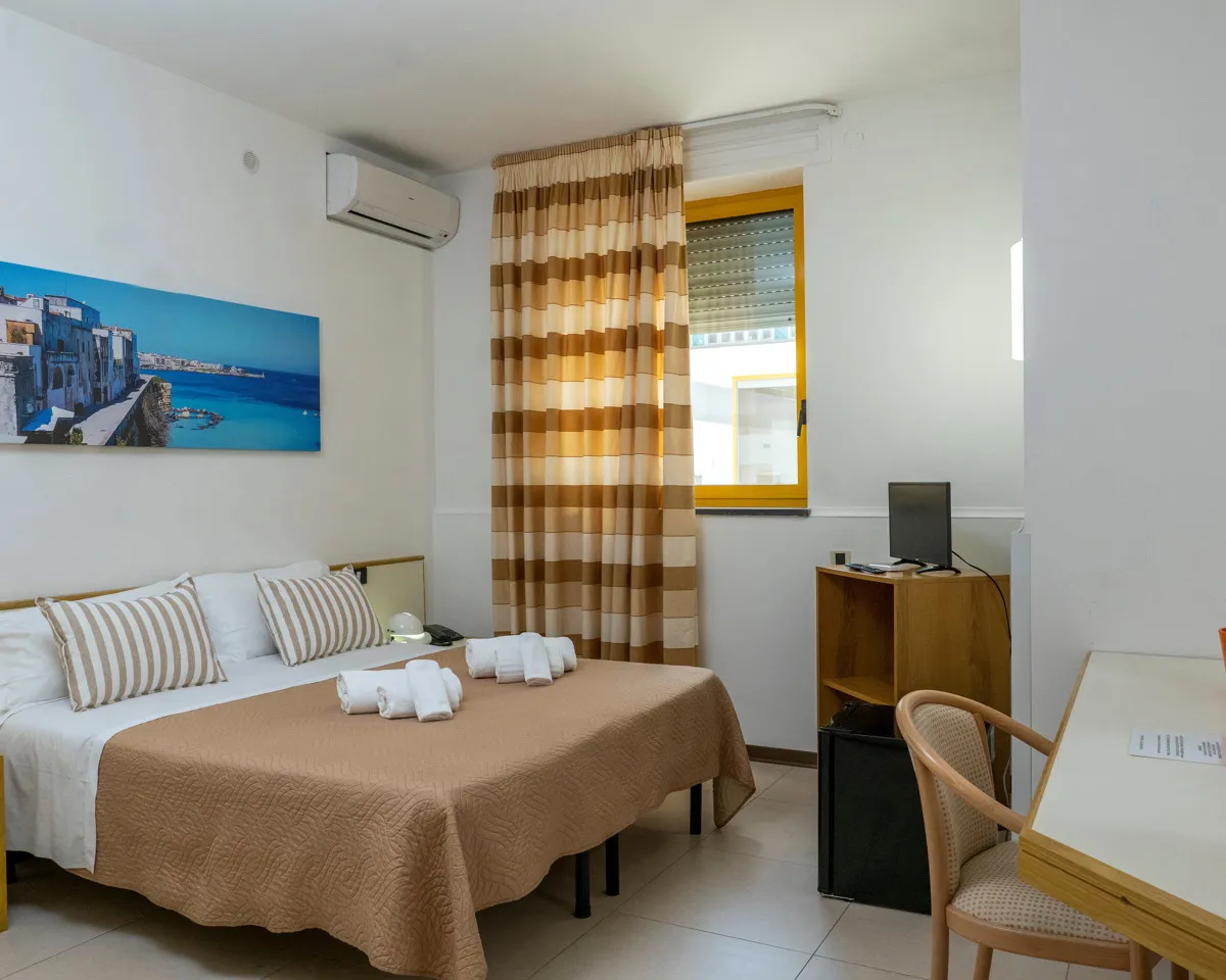 Camera con letto matrimoniale, scrivania, aria condizionata e quadro di Vieste sul mare