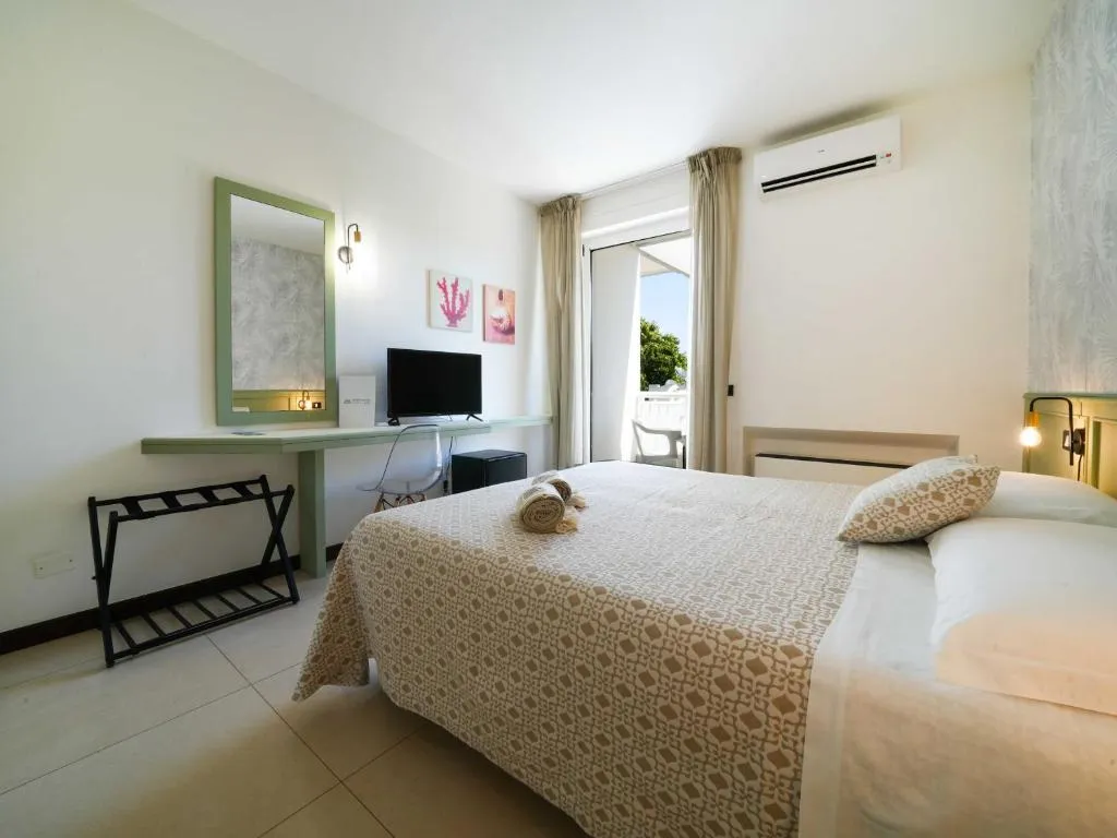 Camera doppia con scrivania, specchio, TV e porta finestra affacciata sul balcone