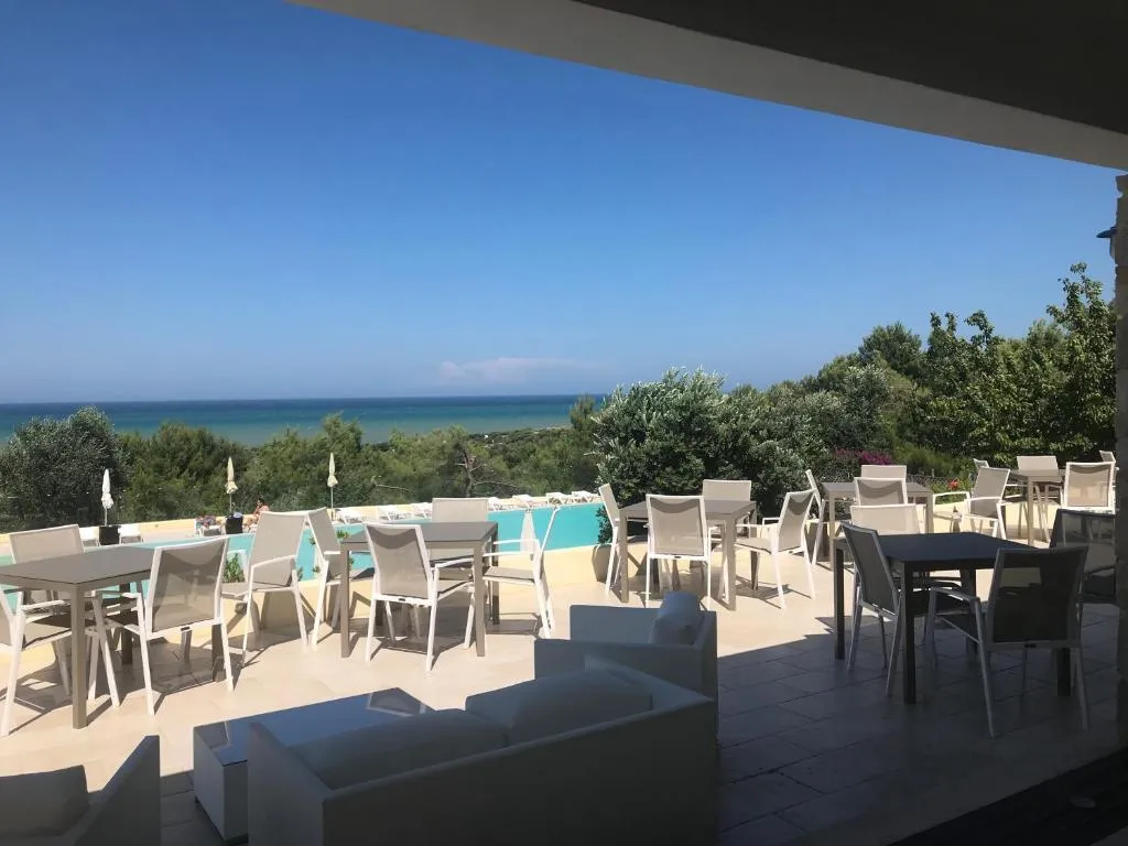 Terrazza con tavoli e divani affacciata su piscina e mare