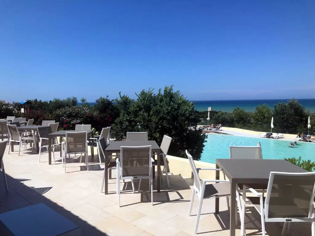 Terrazza ristorante esterna con tavoli e vista mare e piscina