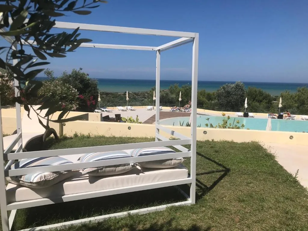 Lettino baldacchino bianco nel giardino con vista sulla piscina e sul mare