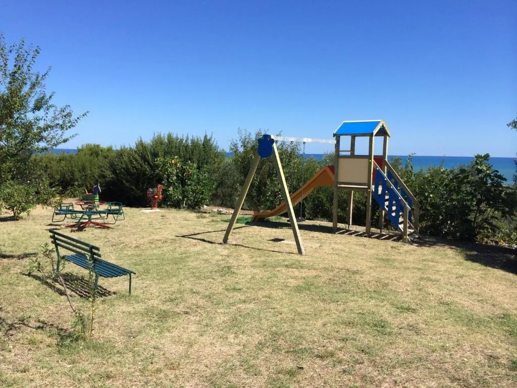 Area giochi per bambini nel giardino con scivolo e altalena e vista mare