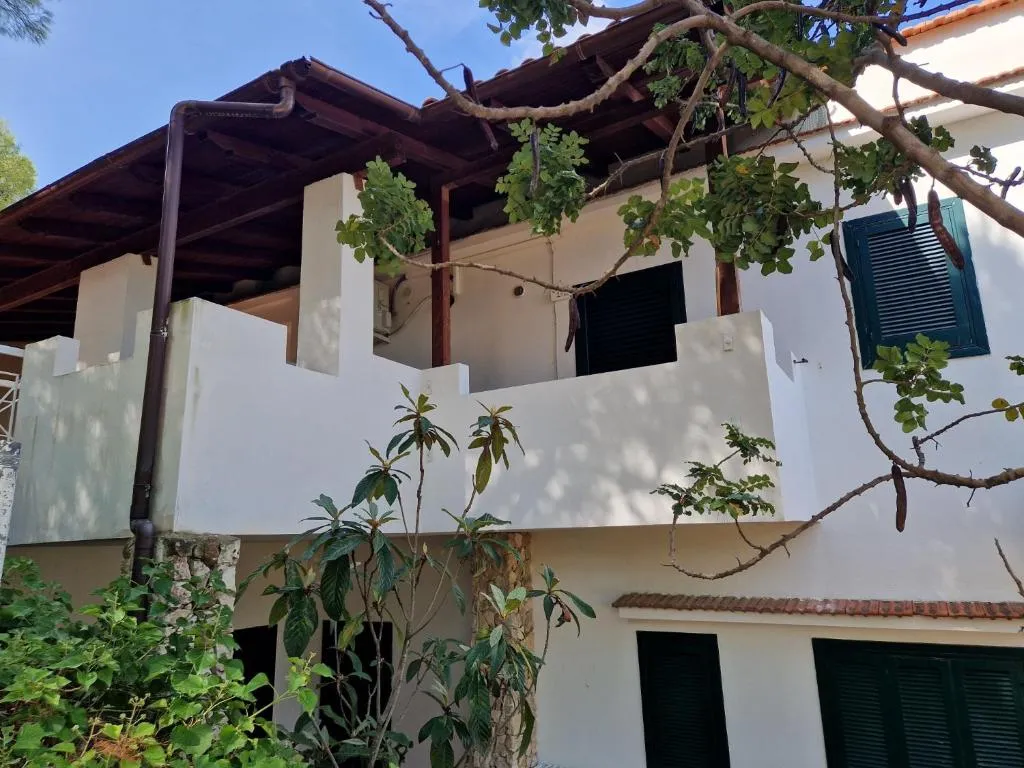 Facciata bianca di villetta con balcone e vegetazione mediterranea