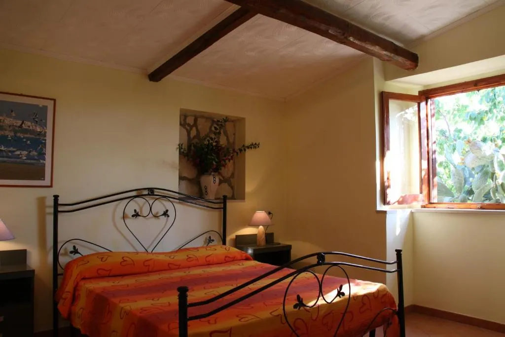 Camera matrimoniale con letto in ferro battuto e travi in legno a vista