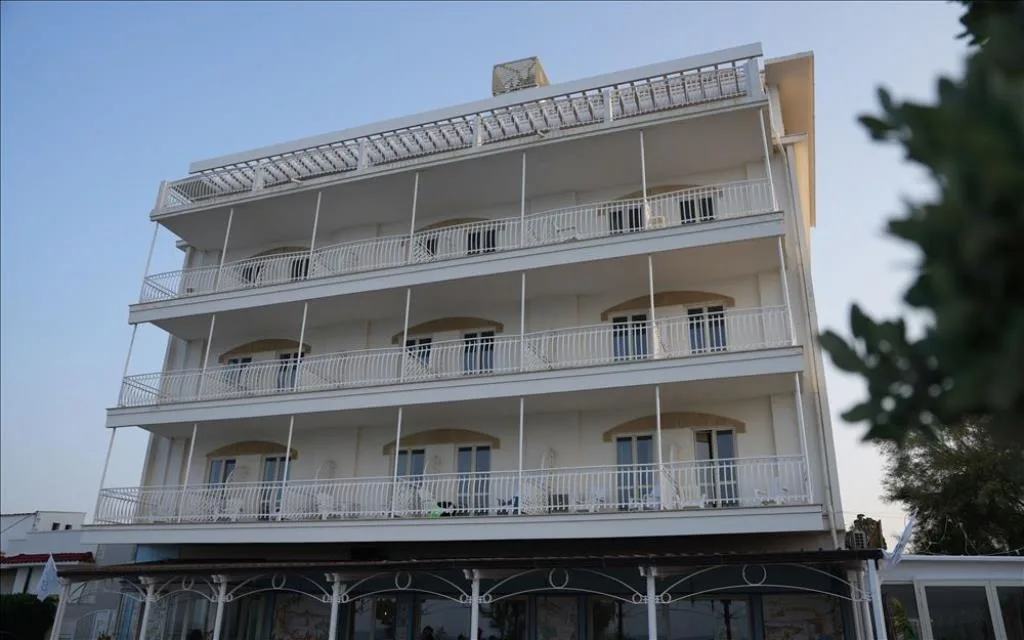 Facciata bianca dell'hotel con balconi e vetrate sul fronte mare