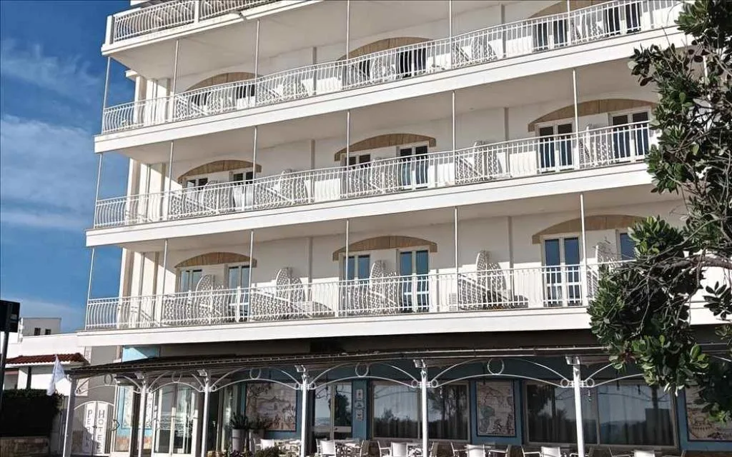Esterno dell'hotel con balconi bianchi e veranda al piano terra