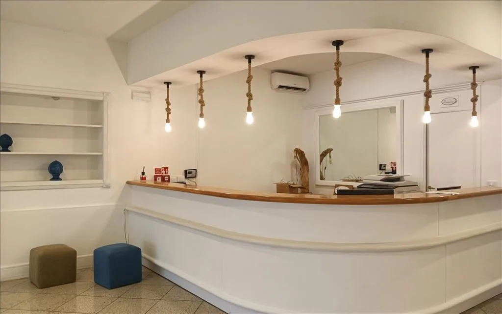Reception dell'hotel con bancone bianco e lampade pendenti decorative