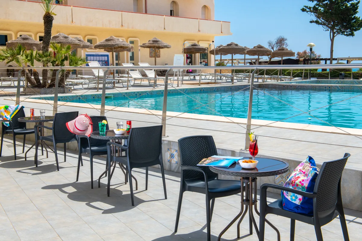 Terrazza bar bordo piscina con tavolini e sedie nere