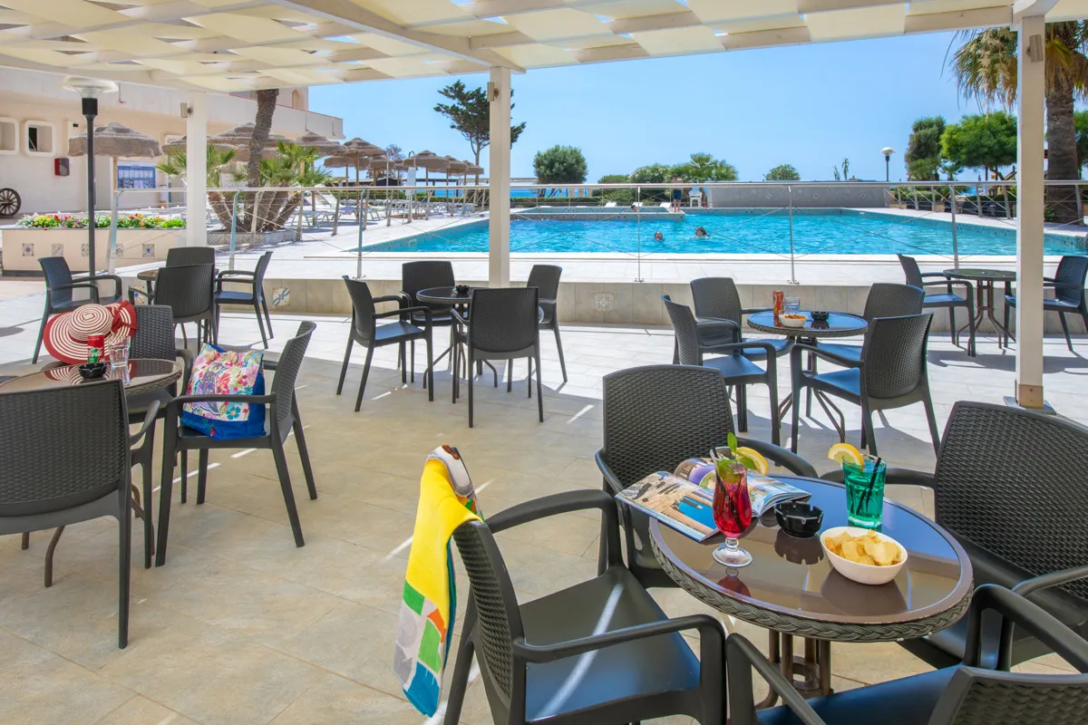 Area lounge coperta a bordo piscina con tavolini e aperitivi