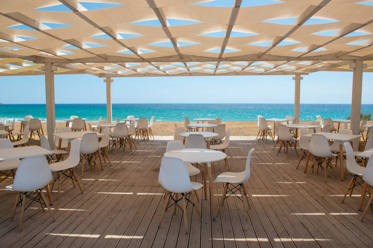 Terrazza ristorante con tavoli bianchi, sedie di design e vista mare