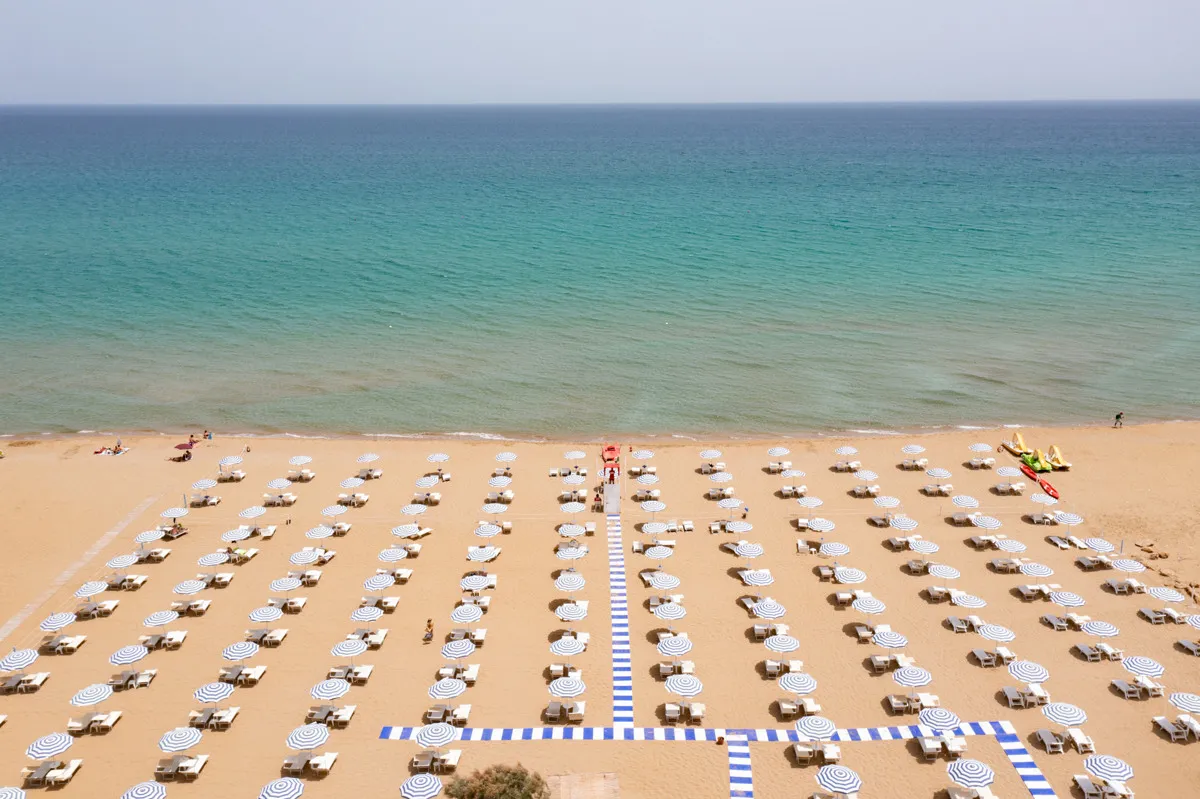 Vista dall'alto della spiaggia con file ordinate di ombrelloni e mare