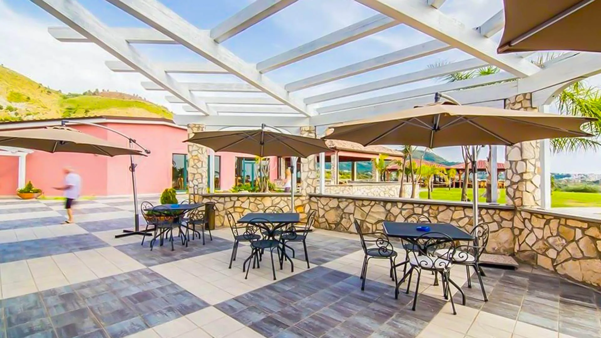 Terrazza esterna con tavoli, sedie in ferro battuto e ombrelloni