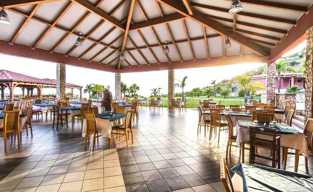 Sala ristorante coperta con tavoli apparecchiati e vista sul giardino