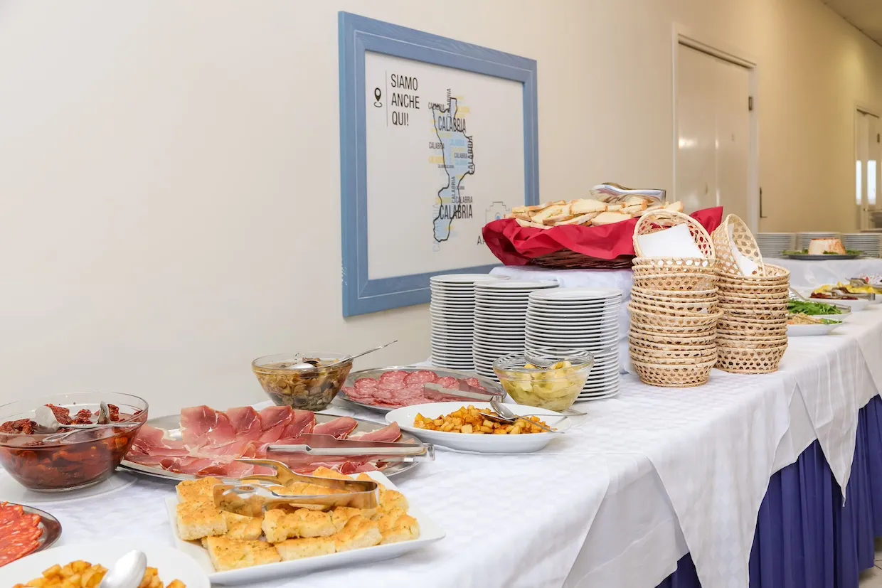 Buffet con antipasti, salumi e pane su tavolo apparecchiato