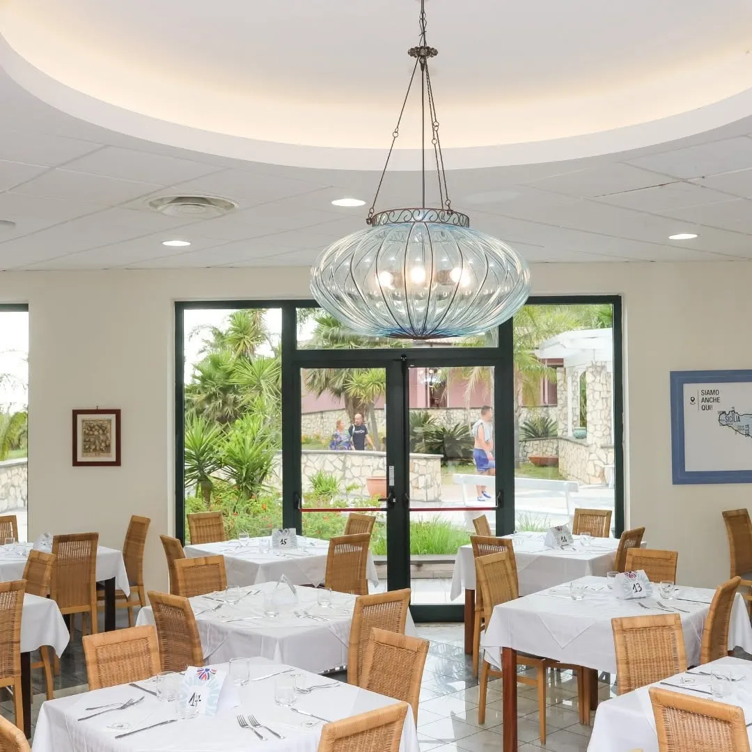 Sala ristorante interna con lampadario in vetro e tavoli apparecchiati