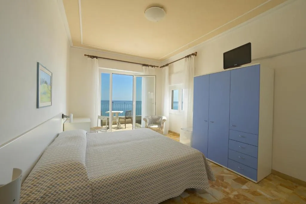 Camera con armadio azzurro, TV a parete e balcone con vista mare