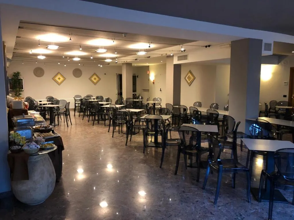 Sala ristorante con tavoli, sedie trasparenti e buffet illuminato