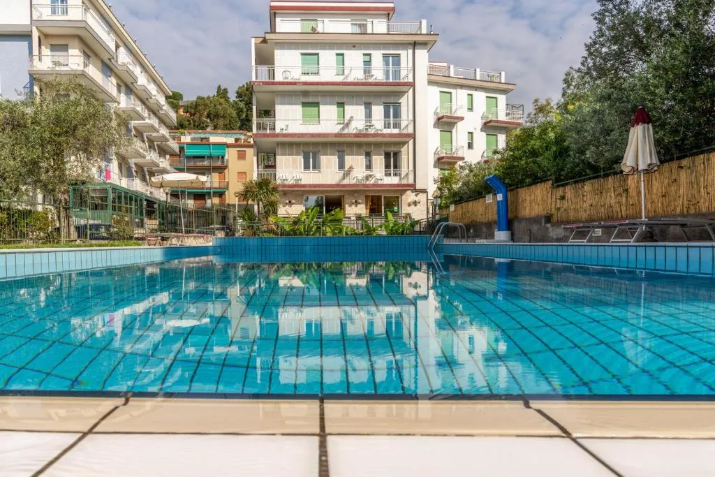 Ampia piscina con vista sull'edificio dell'hotel e ombrellone chiuso
