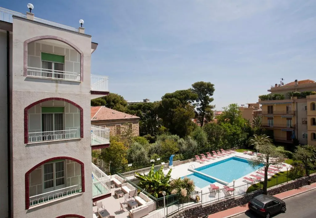 Vista esterna dell'hotel con piscina, lettini e zona relax tra la vegetazione