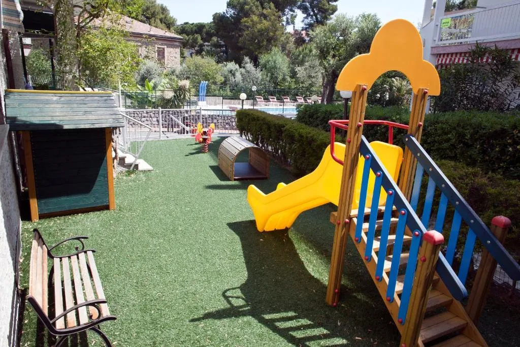 Area giochi per bambini con scivolo colorato e prato sintetico in giardino