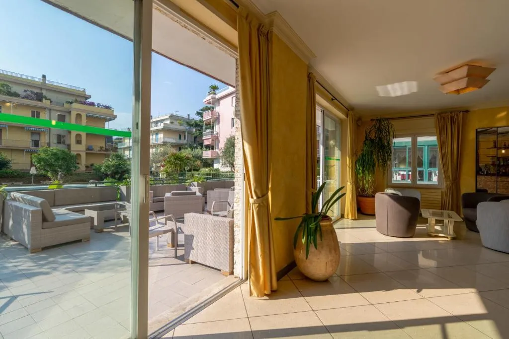 Hall luminosa con divani, ampie vetrate affacciate sulla terrazza e piante
