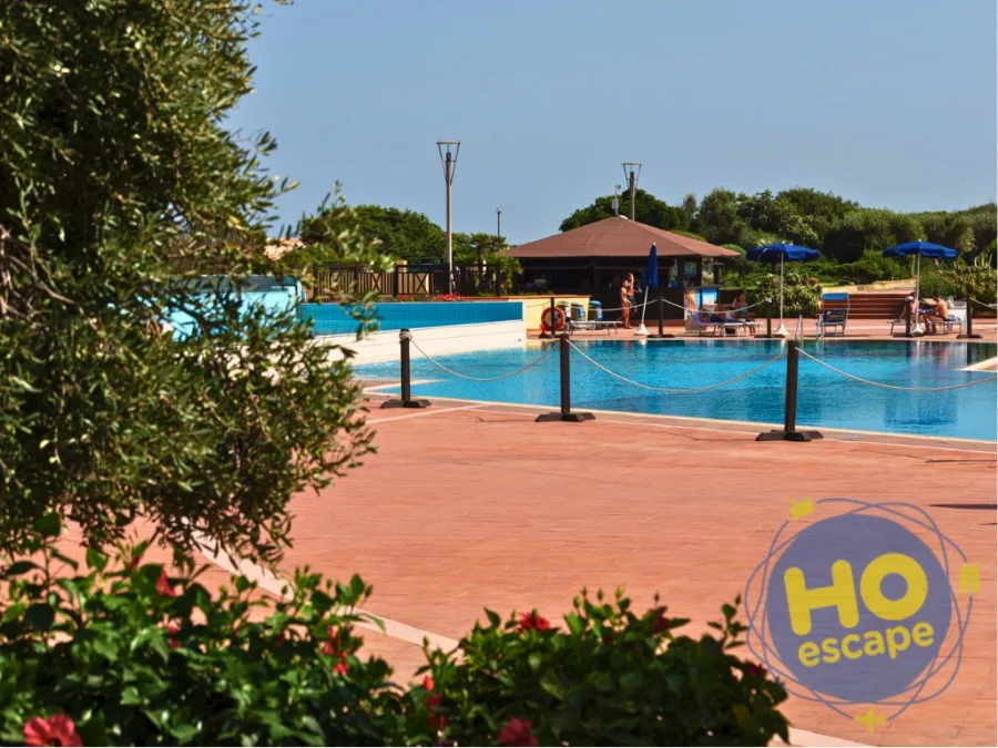 Piscina del resort con bar e ospiti in relax circondata da vegetazione