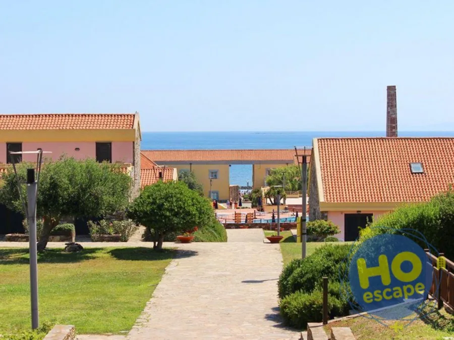Vialetto in pietra tra gli edifici del resort che conduce verso il mare azzurro