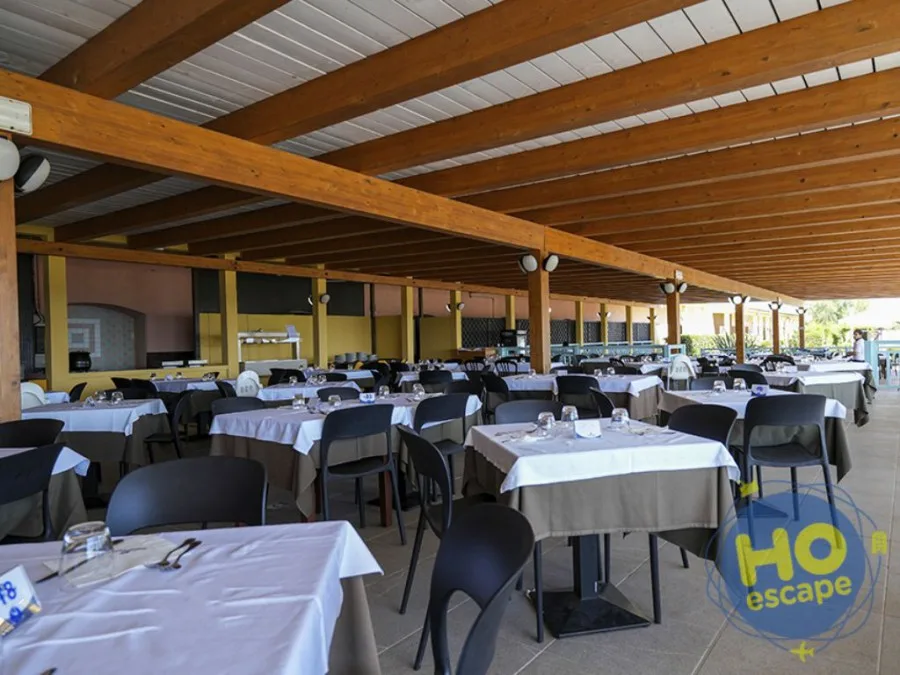 Ristorante coperto con tettoia in legno, tavoli apparecchiati con tovaglie bianche e sedie nere