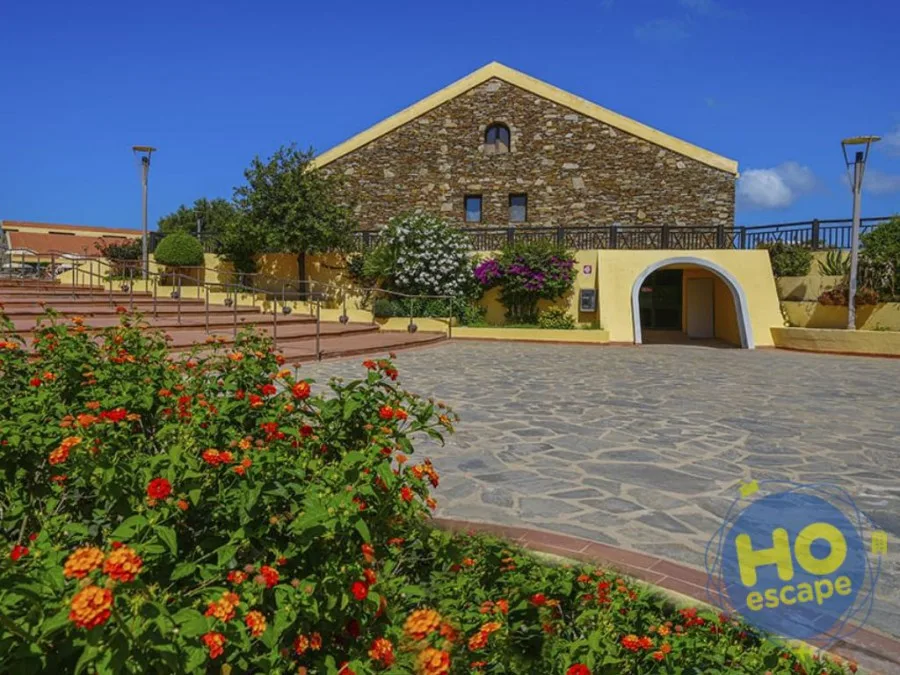 Edificio storico in pietra del resort con fioriere colorate e ampia piazza pavimentata