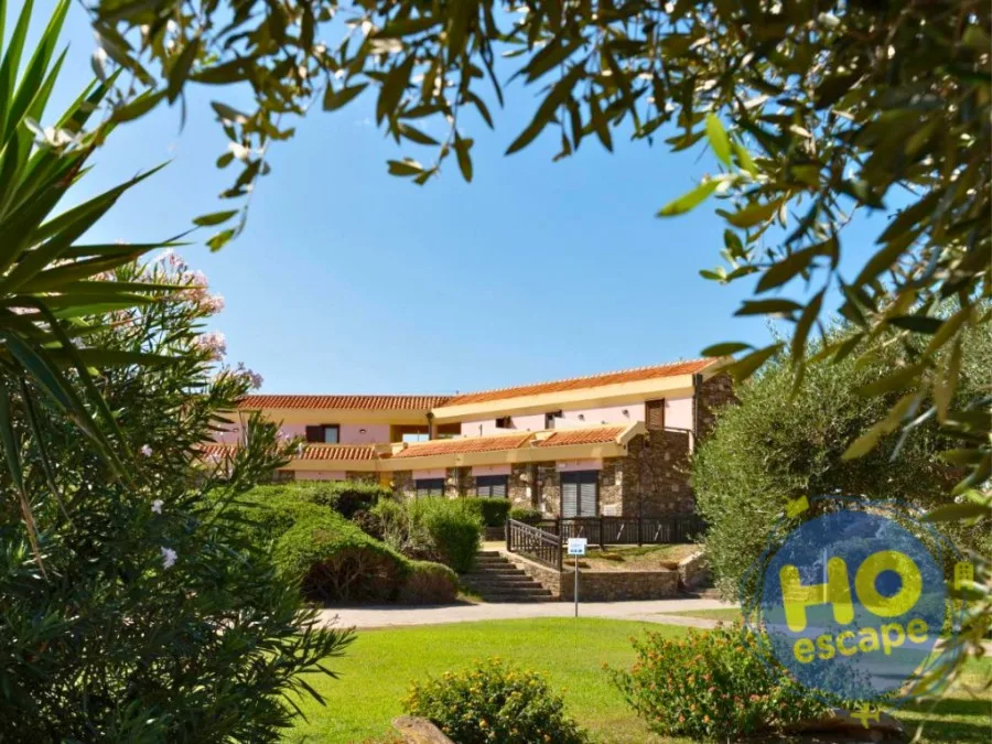 Vista dell'edificio dell'hotel tra la vegetazione mediterranea e il prato verde