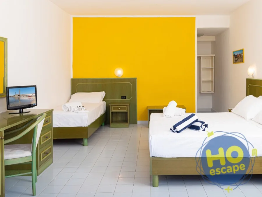 Camera tripla con letto matrimoniale e singolo, parete gialla, TV e scrivania