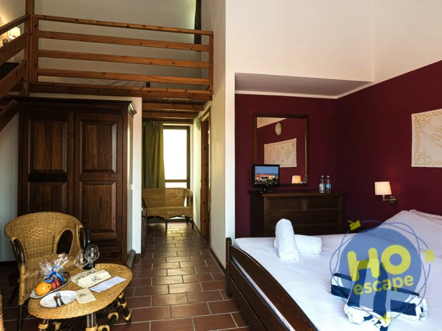 Camera con soppalco in legno, parete bordeaux e angolo salotto in rattan
