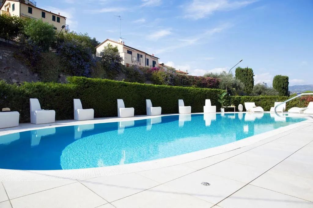 Piscina esterna con poltrone bianche e vista sulle colline circostanti