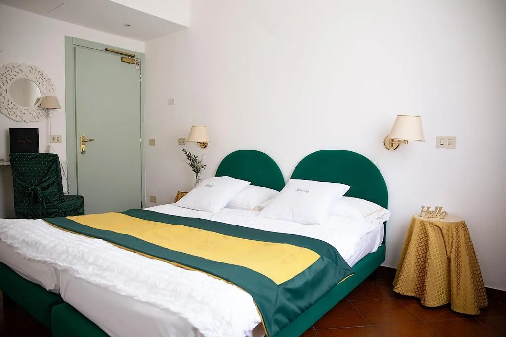 Camera doppia con testiera verde e plaid giallo, arredo essenziale