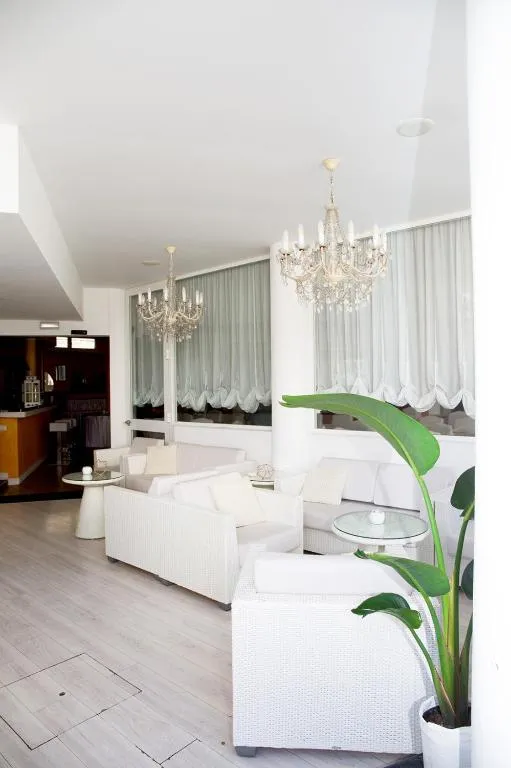 Elegante hall con divani in vetro bianco, lampadari di cristallo e ampie tende