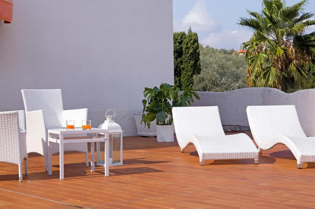 Terrazza solarium con lettini e poltrone bianche in vimini e tavolino con bevande