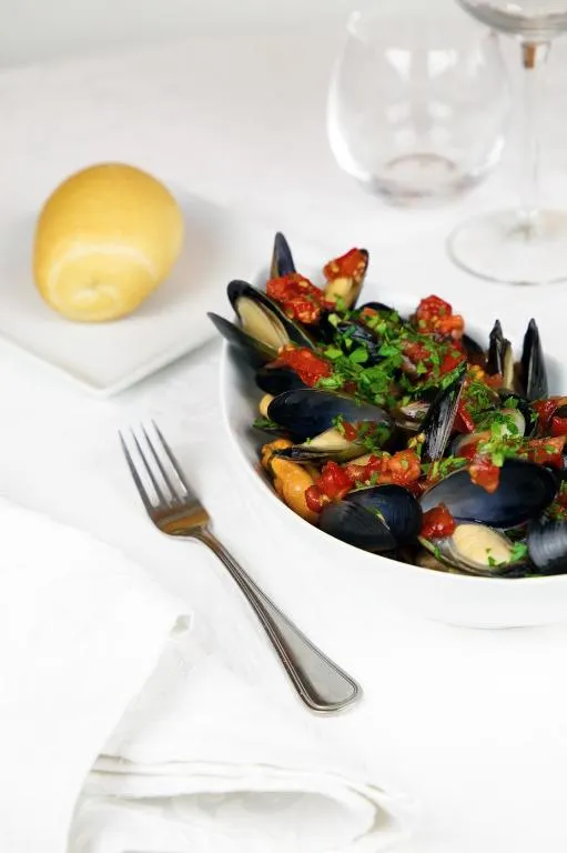 Piatto di cozze con salsa di pomodoro e limone su tavola elegante