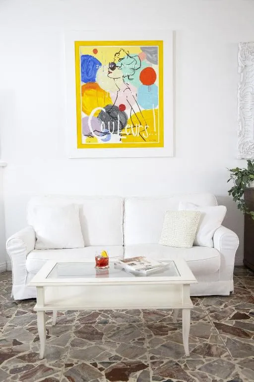 Salottino con divano bianco, quadro colorato e tavolino con aperitivo