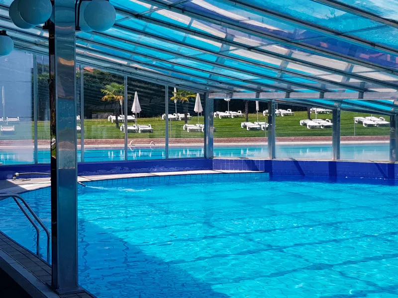 Piscina coperta con struttura in vetro e vista sul giardino esterno