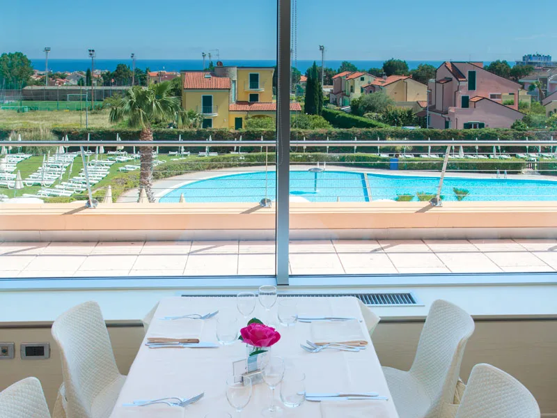 Tavolo apparecchiato al ristorante con vista sulla piscina e sul mare