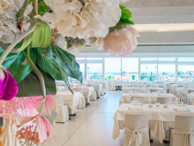 Sala ristorante luminosa con tavoli apparecchiati e decorazioni floreali