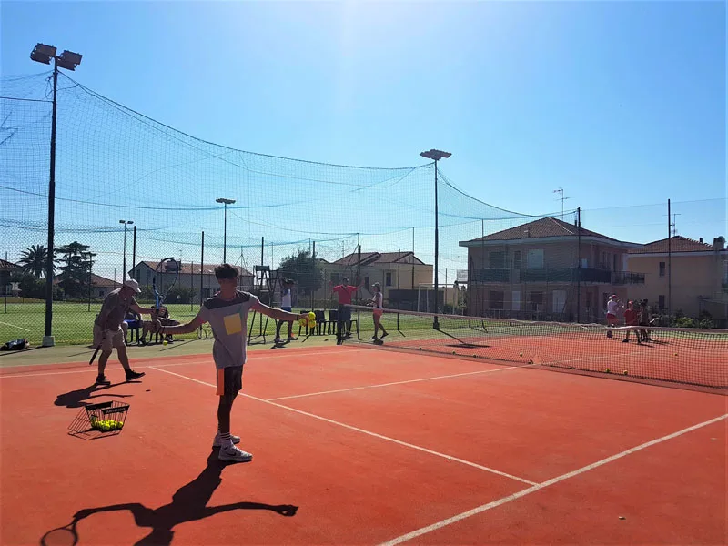 Campo da tennis in terra rossa con giocatori durante una lezione