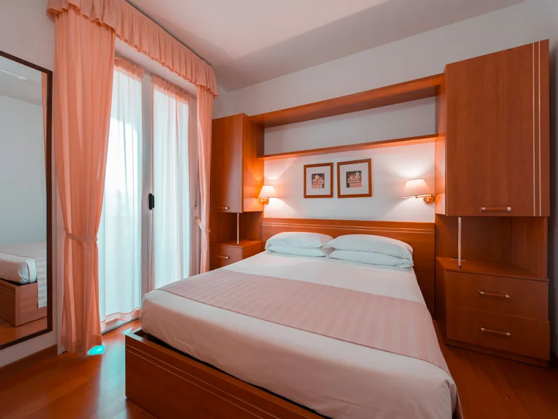 Camera da letto matrimoniale con arredi in legno e tende rosa