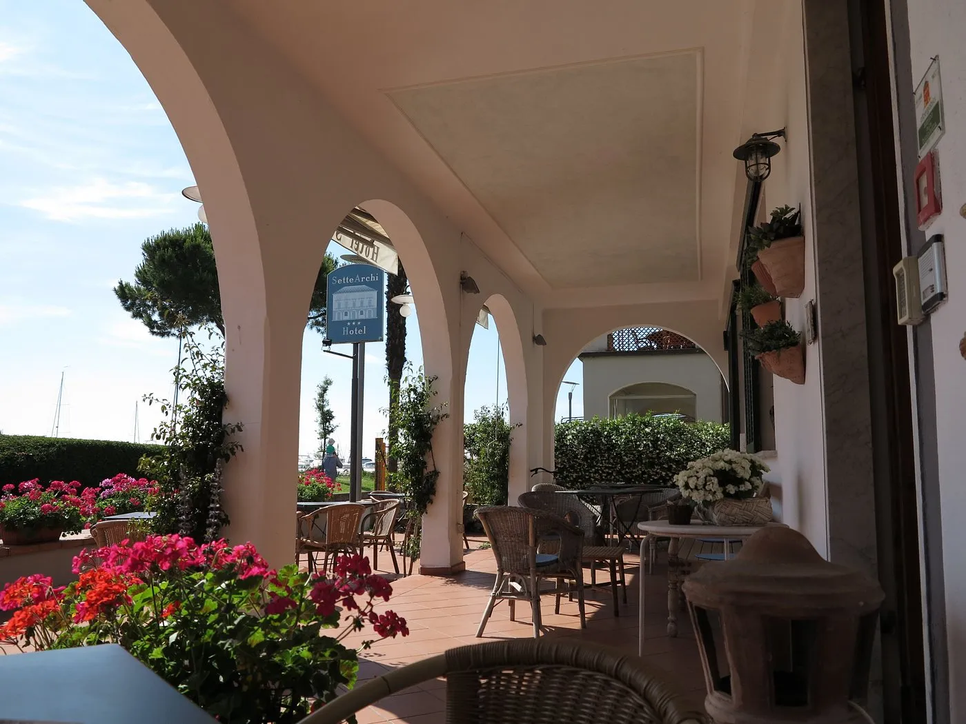 Portico ad archi con tavoli, sedie in vimini e fiori colorati